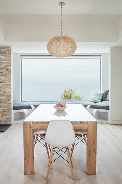 A window seat built into a nook within the dining area of this self build on the coast offers unobstructed views of the sea