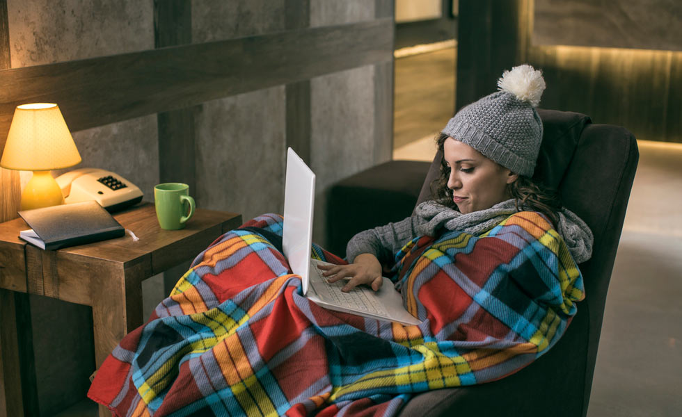 Lady wrapped up in a blanket while on laptop