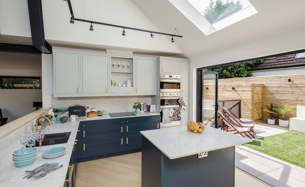 kitchen with dark blue cabinets, an island and bi fold doors