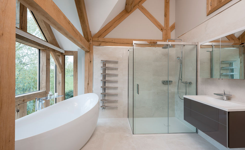 Master en suite with white bathtub and walk in shower and exposed oak beams