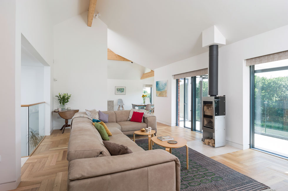 The contemporary living room has a woodburning stove and overlooks the river