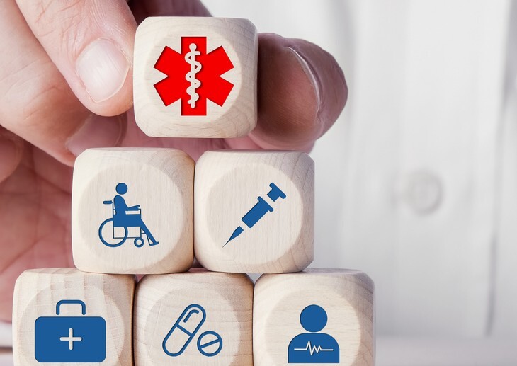 Hand of a doctor placing wooden cubes with medical health icons.