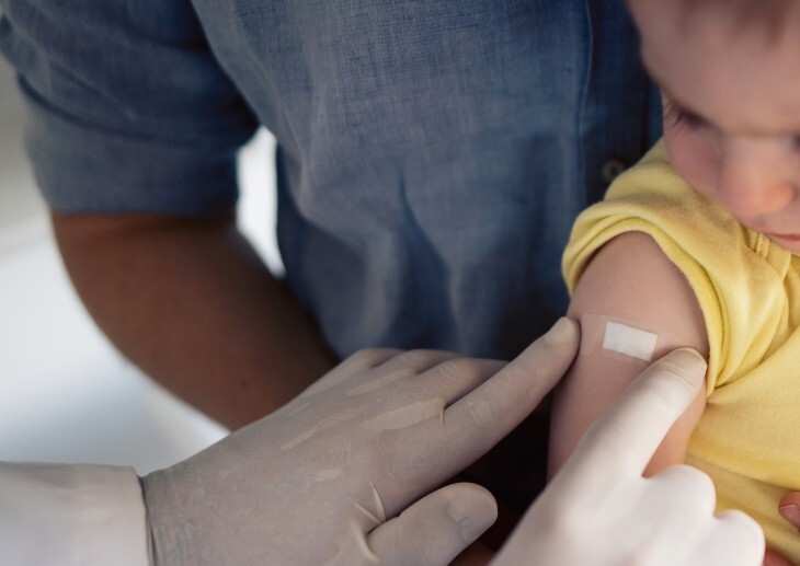 An infant being vaccinated by a healthcare professional
