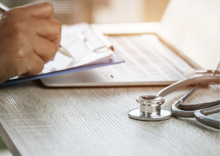 Doctor working in hospital writing on a clipboard.