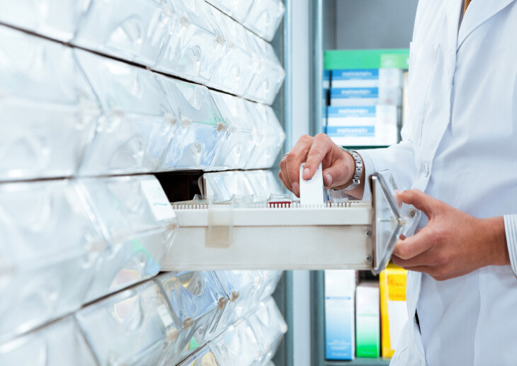 A pharmacist taking medicine from a drawer.