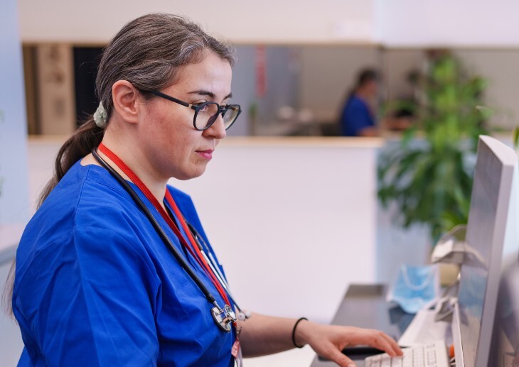 Healthcare professional working on computer at reception desk