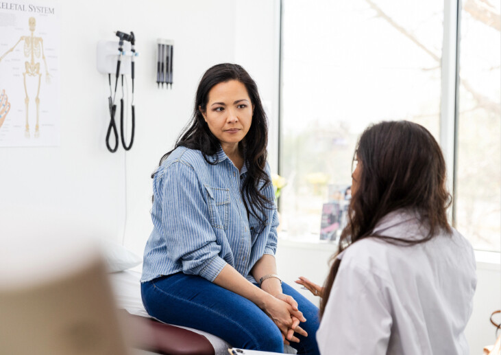 A female patient in a GP office speaking with a female doctor.