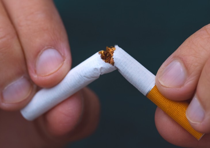 Hands holding a broken cigarette.