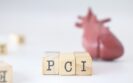 Three wooden blocks with the letters PCI and a human heart model blurred in the background to illustrate P2Y12 inhibitor monotherapy being found to have lower MACCE risk than aspirin after percutaneous coronary intervention