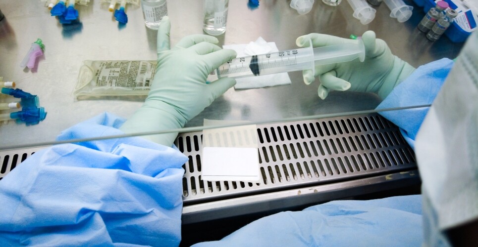 A pharmacy professional in full PPE working in an aseptic department and preparing medicines to illustrate new legislation around supervision and aseptic services
