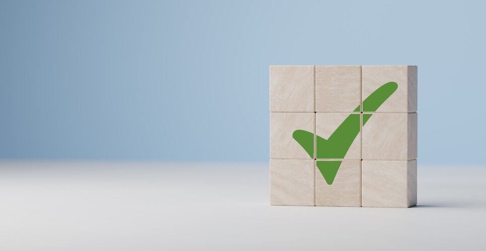 Nine wooden blocks stacked together with a green tick across them all on a white and blue background to illustrate the first needle-free anaphylaxis treatment being approved in the UK