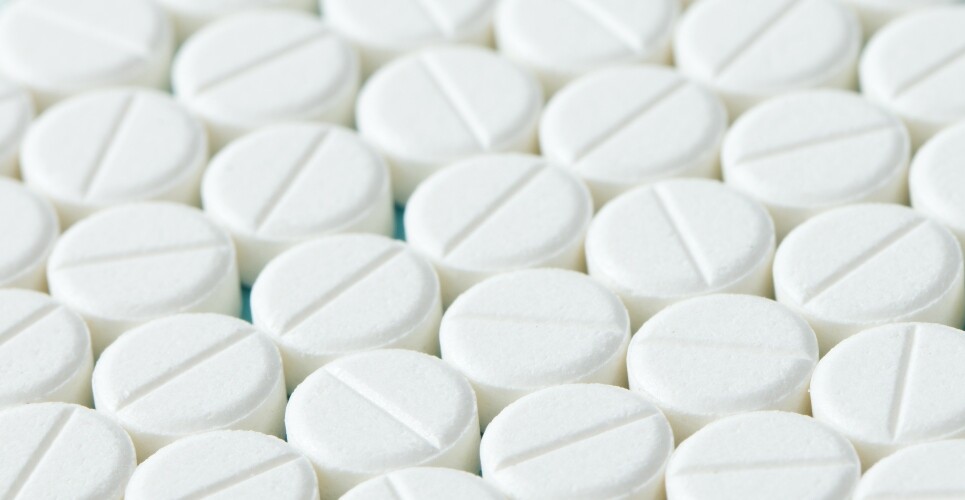 Close up of white round tablets with lines down the centre lined up to represent beta-blockers and illustrating the differing evidence of their use post myocardial infarction in patients with LVEF