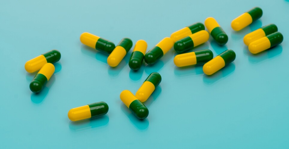 Green-yellow capsules spread on blue background to illustrate the finding that tramadol harms outweigh limited benefits for chronic pain