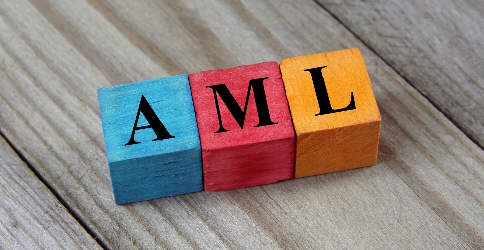 A set of three wooden blocks, one blue, one red and one orange, with the letters AML on them in black lettering on a diagonal wooden plank background to illustrate universal CAR T-cells showing promise against AML
