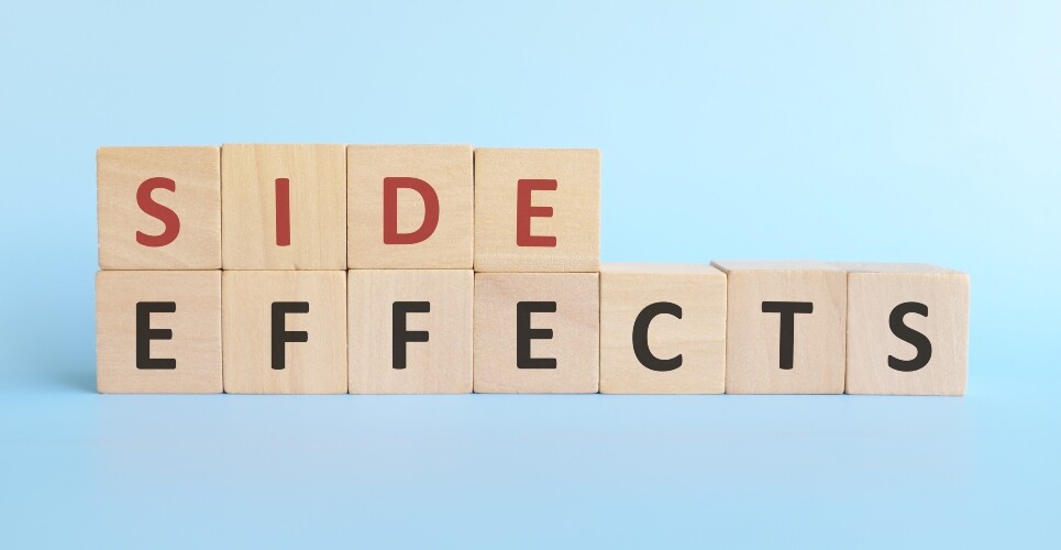 Wooden blocks with letters spelling out side effects on a blue background with the first word in red and the second in black to illustrate the finding that mostadverse effects listed for statins are not attributable to the drug