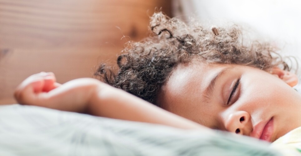 A child asleep in bed to illustrate that intranasal saline confers benefits over steroids in childhood obstructive sleep-disordered breathing