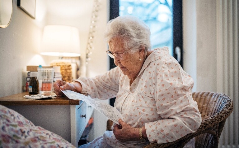 Senior woman reading patient information leaflet included with medication to illustrate the finding that pharmacist-led discharge shows targeted benefits for low-literacy patients