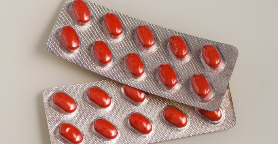 Two blister packs of opaque red tablets to illustrate isotretinoin and new prescribing requirements from the MHRA