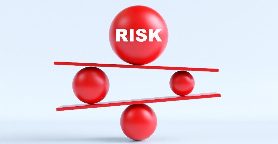 3D illustration of red spheres balancing on tilted platforms, with a large ball labelled ‘RISK’ on top to illustrate the finding that serious infection risk is broadly comparable across psoriasis therapies