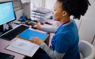 practice nurse at desk looking at computer