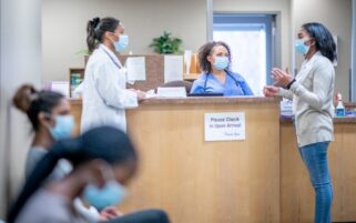 Receptionists And Patients In Waiting Room