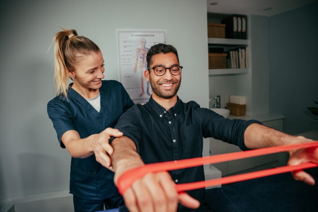 physiotherapist assisting male patient holding resistance band