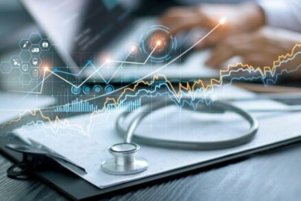 stethoscope resting on clipboard on a desk as medic looks at data on computer in background
