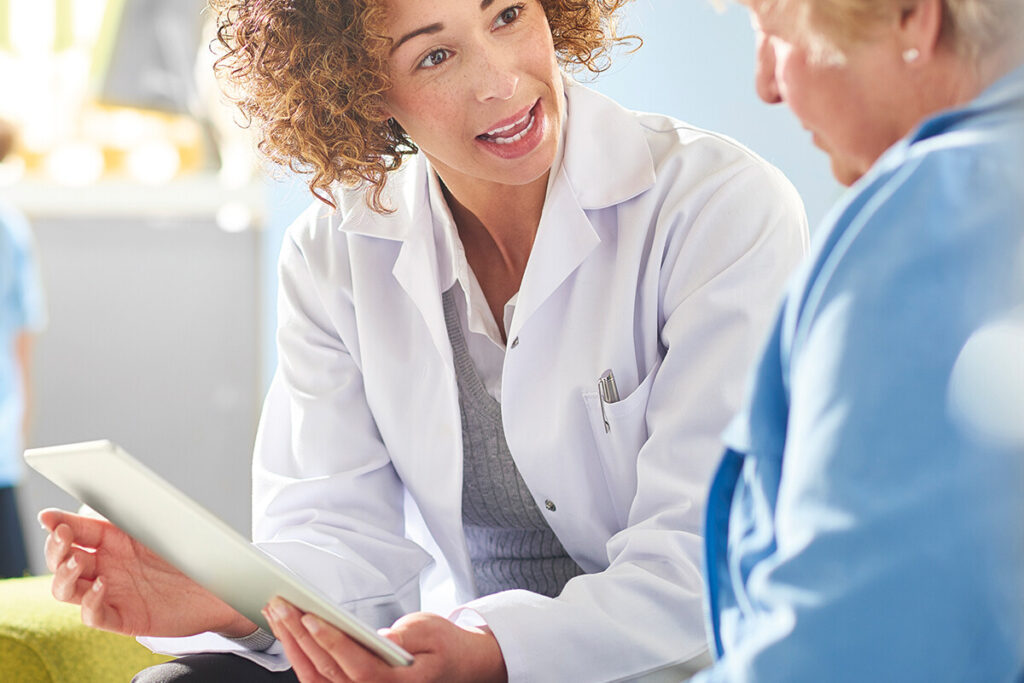A female pharmacist sits with a female patient
