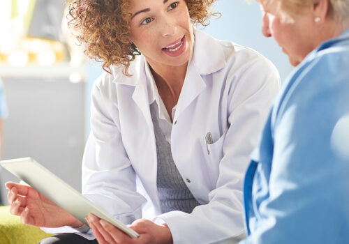 A female pharmacist sits with a female patient