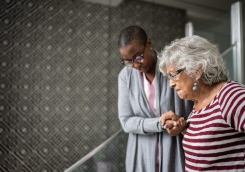 Community health and wellbeing workers (CHWWs) helping a senior woman walking the stairs