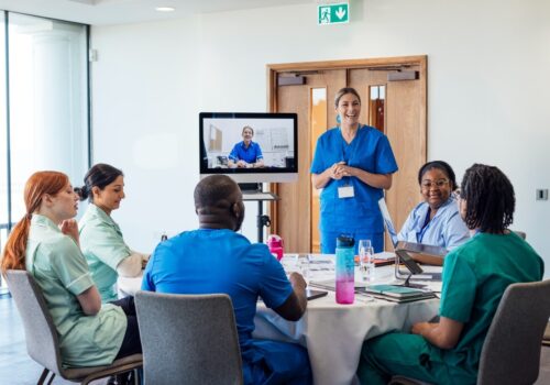 A group of medical professionals sitting around a table, taking part in a training meeting