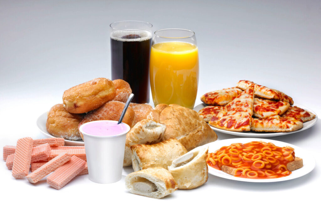 Ultra-processed foods, including pizza, coke, orange juice, doughnuts, sausage rolls and spaghetti hoops.