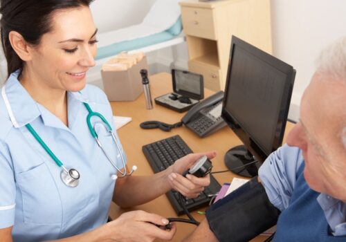 A nurse taking a male patient's blood pressure.