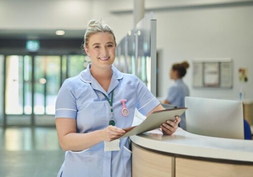 nursing associate standing at primary care reception desk