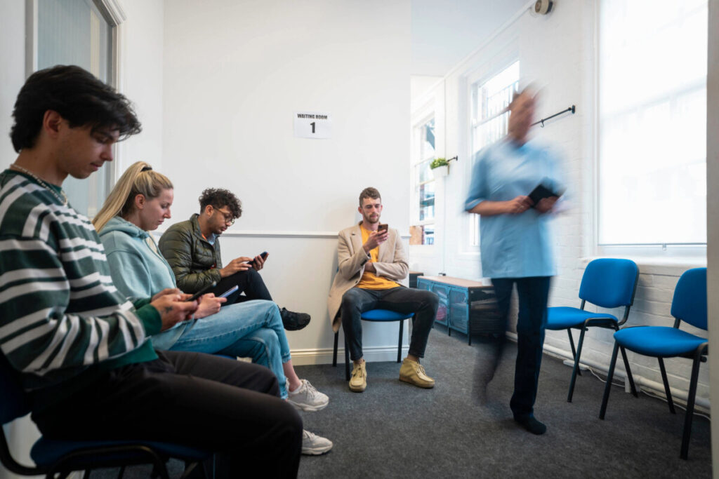 Patients sitting in a GP waiting room.