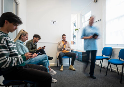 Patients sitting in a GP waiting room.
