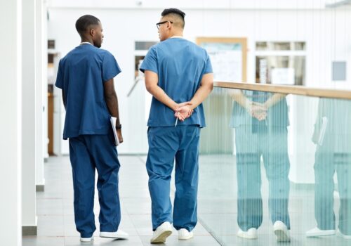 Two PAs walking down a corridor.