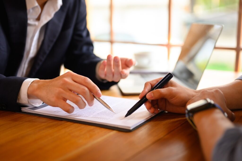 Two people signing a contract on a table.