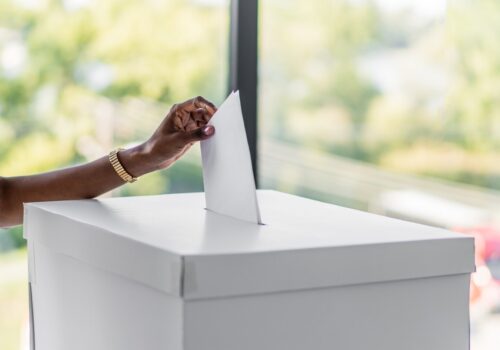 A hand putting a ballot paper in a ballot box.