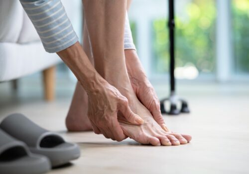 Senior woman suffering from pain in ankle at home.