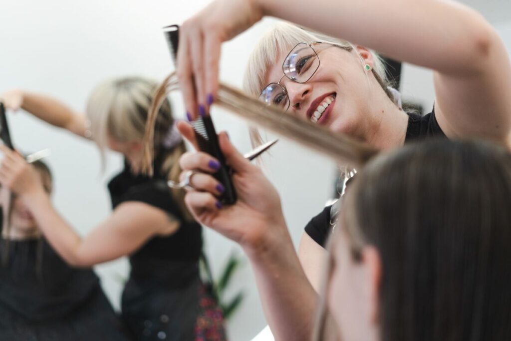 smiling hairdresser cutting woman's hair