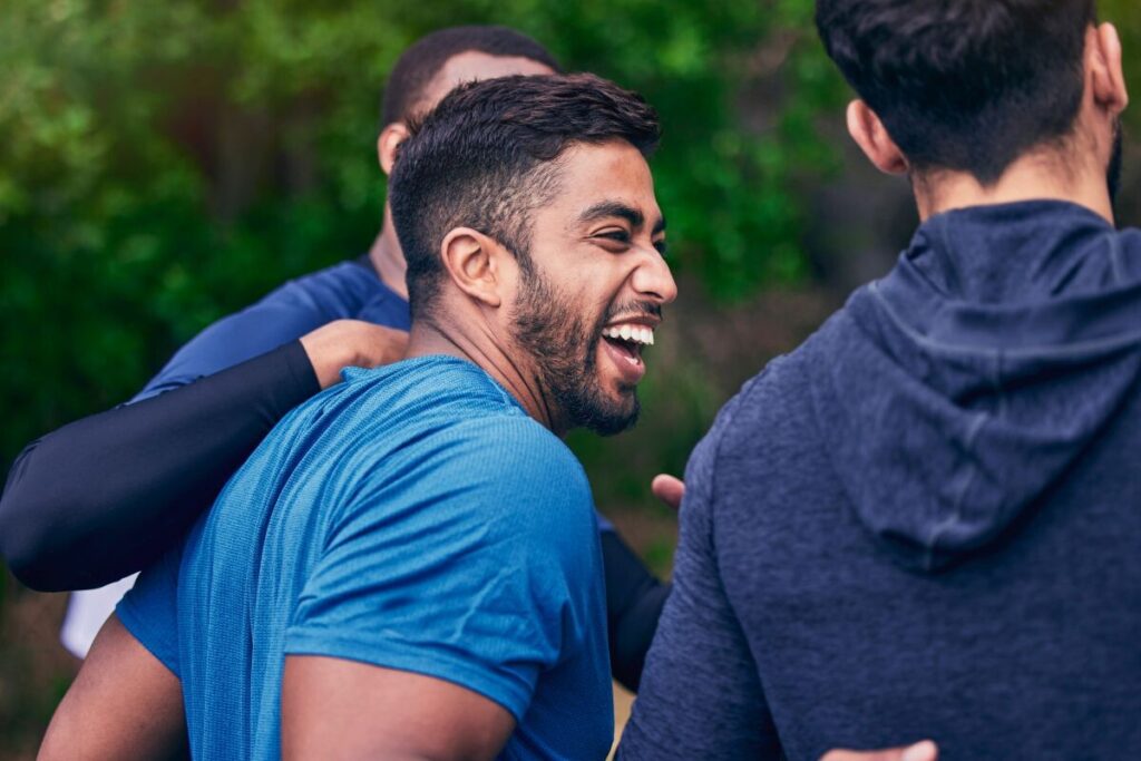 Young Indian man laughing with friends during exercise session in a park
