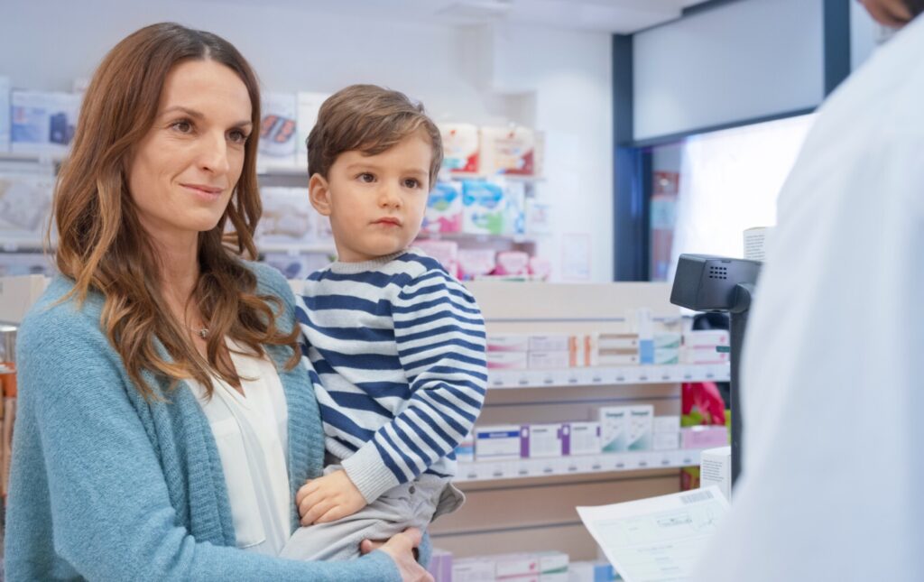 women with child in her arms talking to a pharmacist in a pharmacy