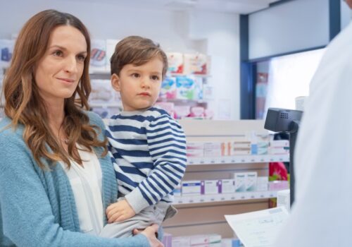 women with child in her arms talking to a pharmacist in a pharmacy