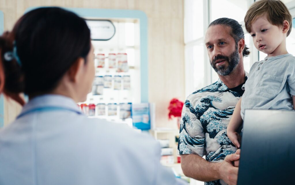 Pharmacist talking to father holding child