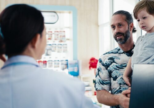 Pharmacist talking to father holding child