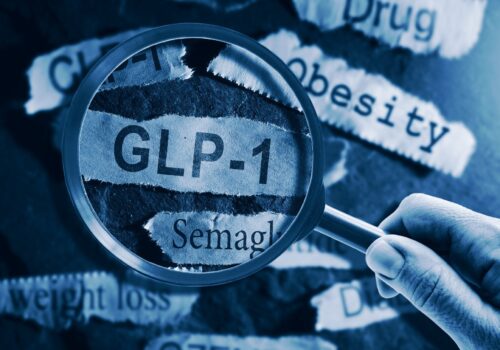 magnifying glass over key words associated with weight loss, including GLP-1, obesity, weight loss, drug