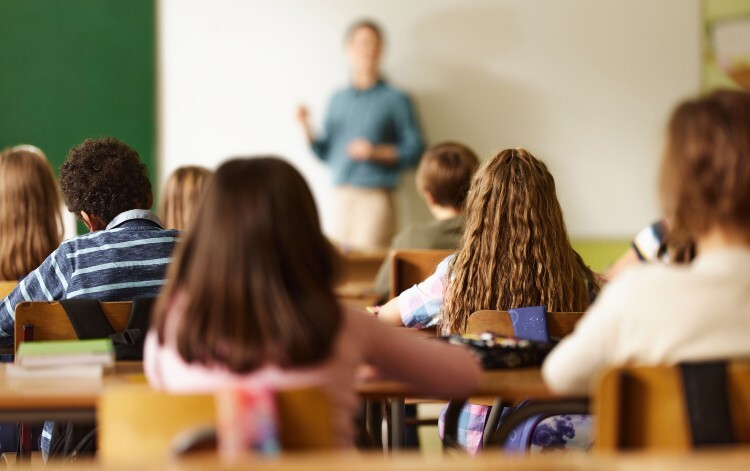Children sitting in a classroom with in front of a teacher