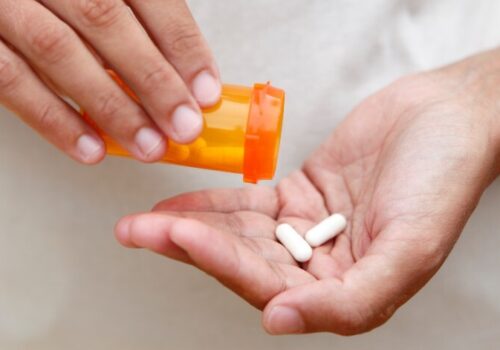 Person tipping some white pills into their palm