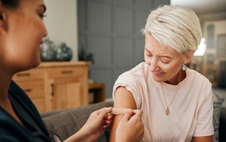 Pharmacist administers vaccine to patient sitting on a sofa